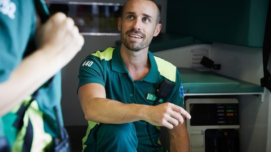 Paramedic discussing with coworker while sitting in ambulance in parking lot