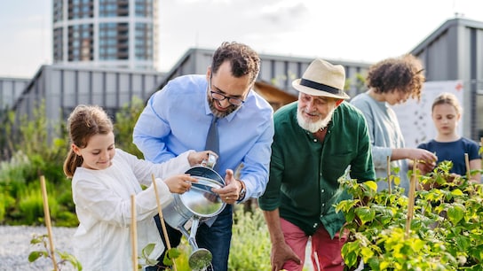 Neighbours taking care together of their community garden in a city. 